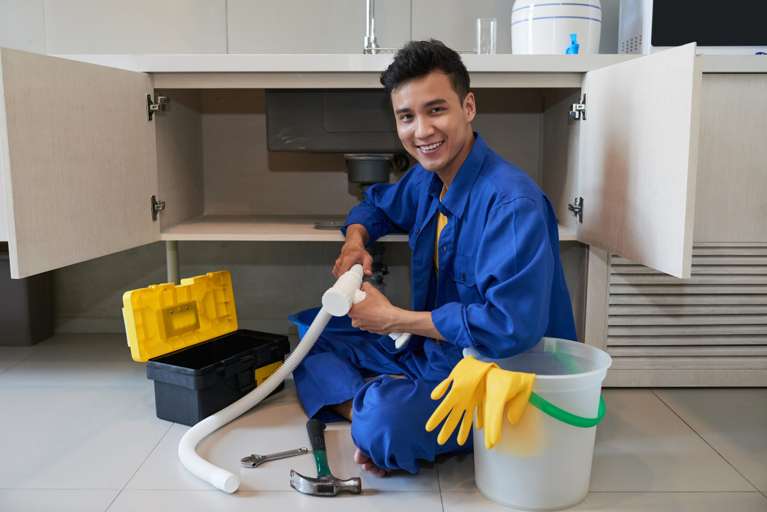 Portrait of smiling Vietnamese plumber repairing sink